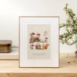 Affiche cosy représentant une scène forestière avec champignons, panier de pique-nique, pâtisserie et écureuil roux.