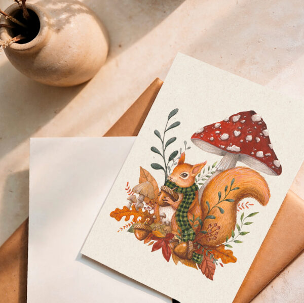 Carte illustrée “Un automne cosy” avec un écureuil tenant un gland, entouré de feuilles et d’un champignon rouge. Illustration automnale douce et poétique signée L’atelier de l’Écureuil.
