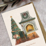 Salon décoré pour Noël avec cheminée allumée, sapin et petit écureuil devant un fauteuil.