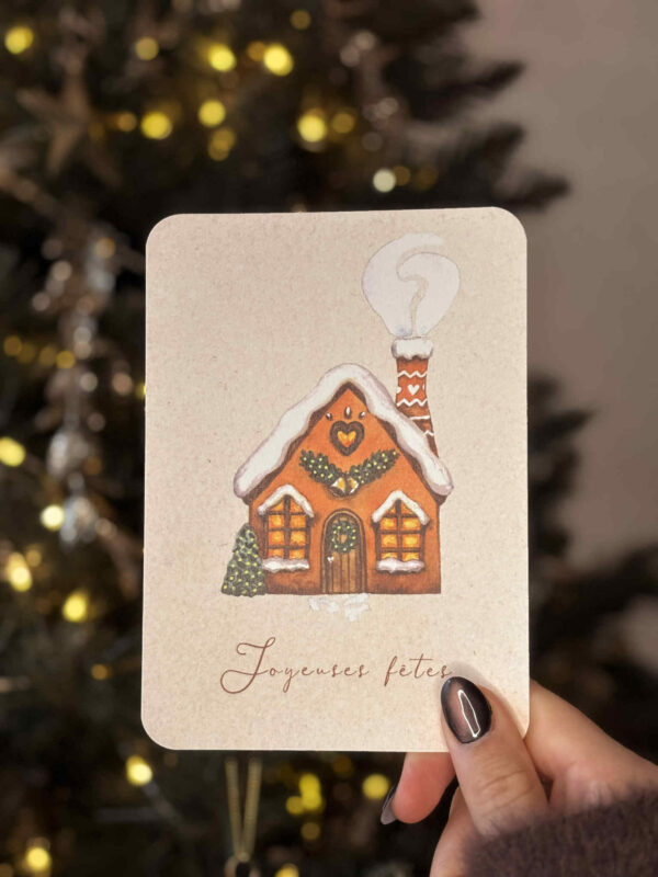 Carte de vœux illustrée représentant une maison pain d’épices enneigée et décorée pour Noël.
